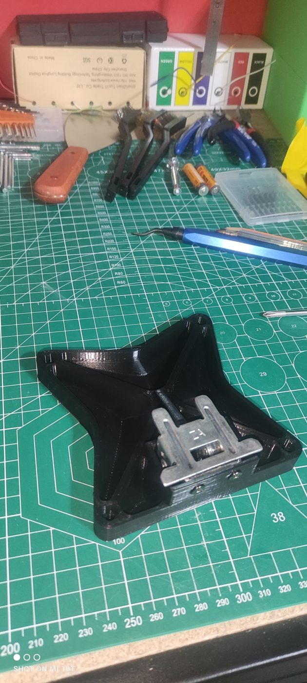 Platine imprimée en 3D posée sur un tapis de découpe, à côté de sa contreplaque métallique