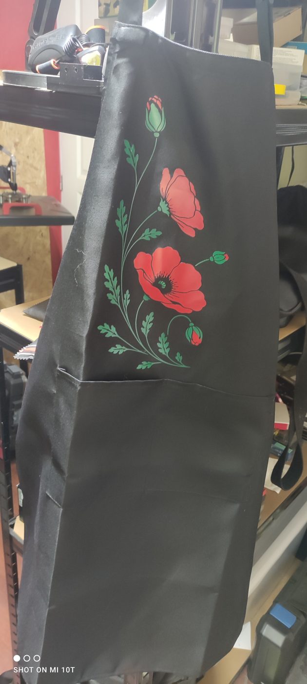 Tablier sombre marqué d’un motif de coquelicots rouges et de feuillage vert